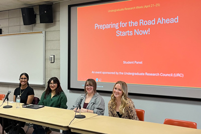 Student panel sitting at the front of a classroom with a powerpoint presentation behind them that reads "Preparing for the Road Ahead Starts Now!"
